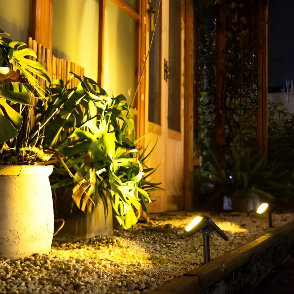 Solar path lights outdoor near a potted plant, providing focused illumination for a cozy entrance.