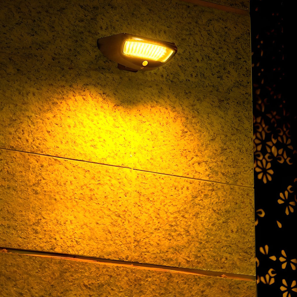 Solar powered motion sensor wall light casting warm light on a garden pathway.