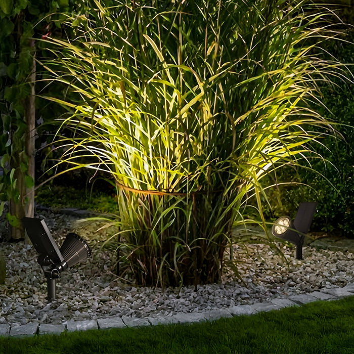Solar powered spotlights used to highlight tall ornamental grass in a garden bed, providing focused outdoor accent lighting.