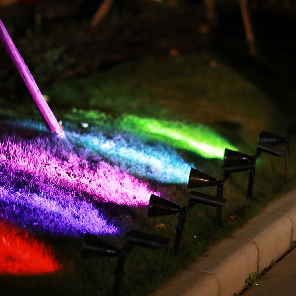 Solar powered spotlights projecting colorful RGB lighting effects onto outdoor ground for decorative landscape illumination.