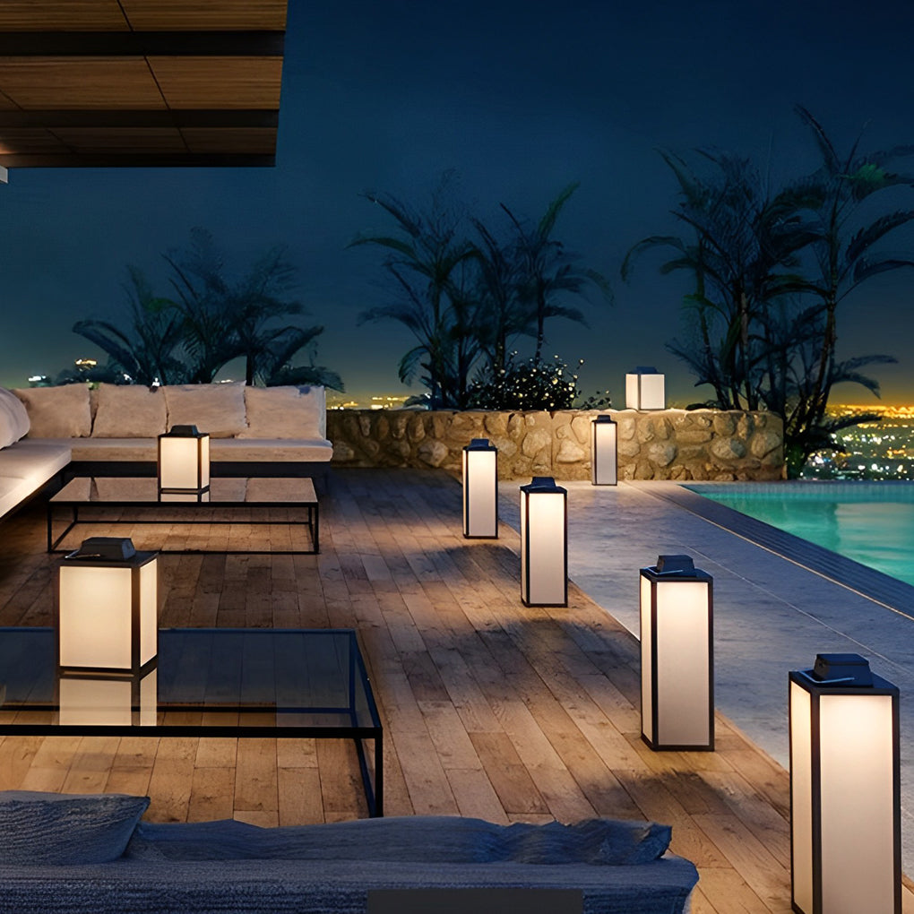 Square handheld lantern casting soft light on poolside deck with modern furniture.