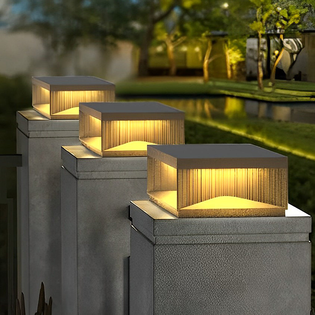 Square outdoor pillar lights installed on concrete posts illuminating garden pathway edge.