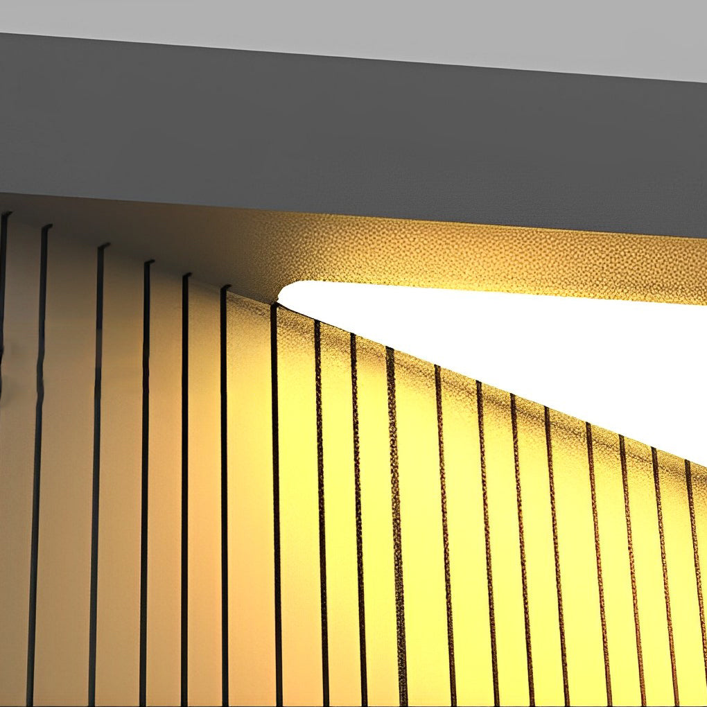 Close-up detail of square outdoor pillar lights showing vertical slatted diffuser and warm light output.