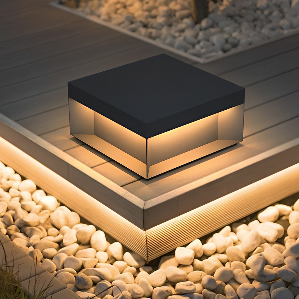 Square solar deck light illuminating wooden deck corner with warm ambient glow.