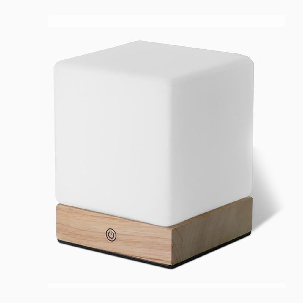 Square wood lamp with a soft glow, placed on a minimalist wooden table.
