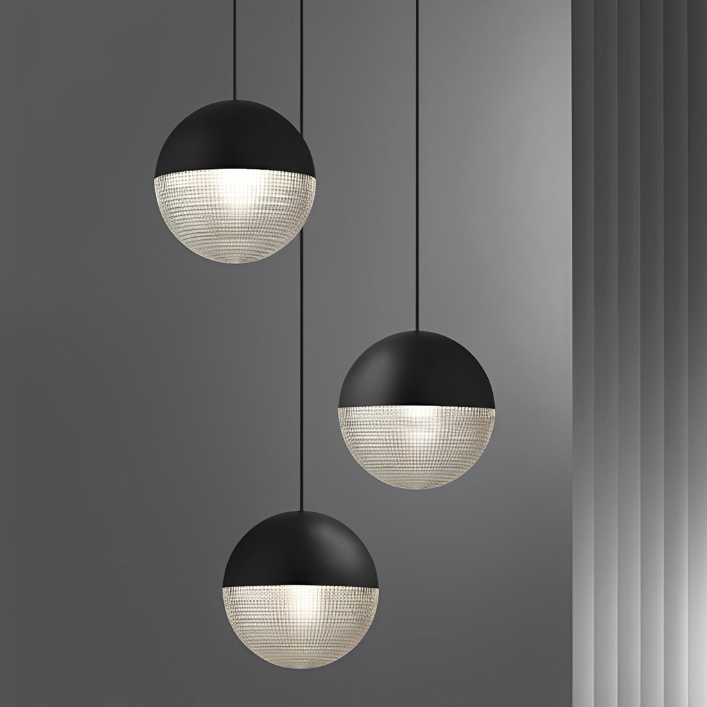 Trio of black globe pendant lights in a staggered cluster with ribbed glass on grey wall.