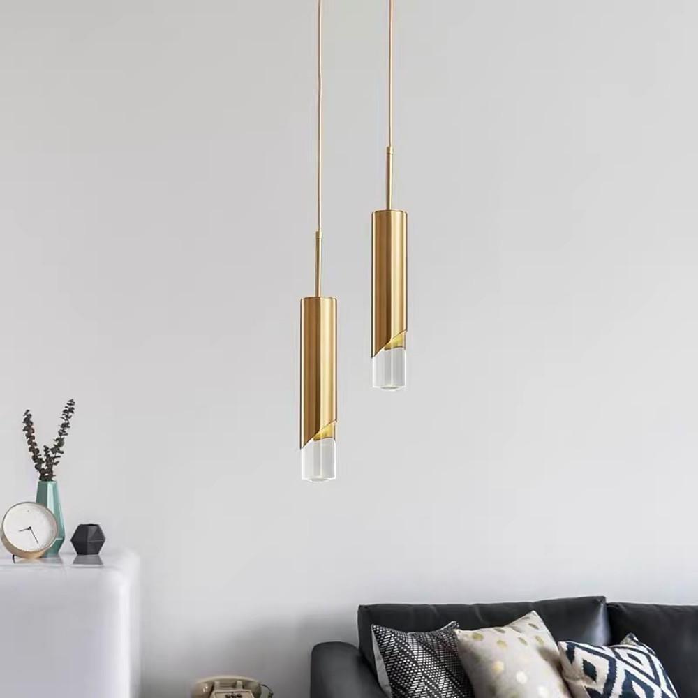 Staggered duo of Slanted Gold Cylinder Pendant fixtures in a modern living room lounge space.