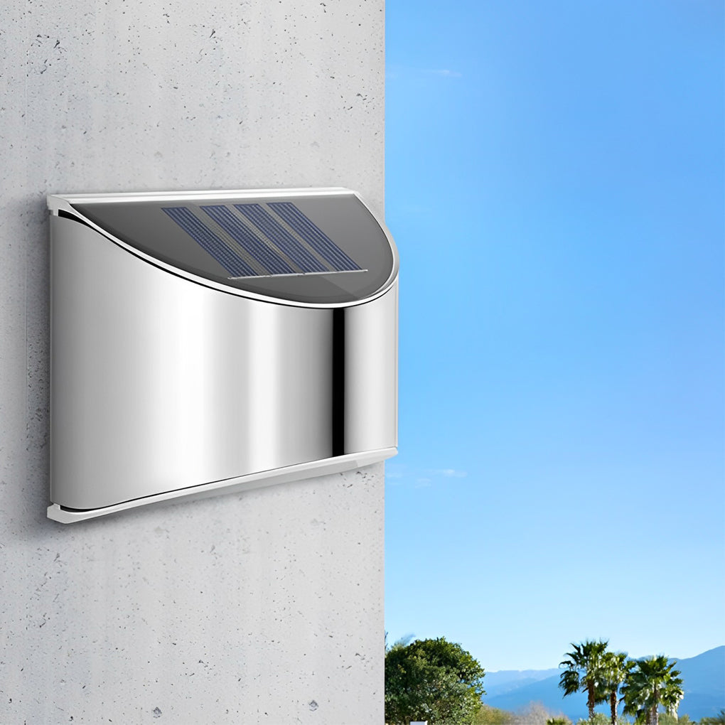 Stainless steel wall lamp with a curved solar panel top, emitting soft light at night.