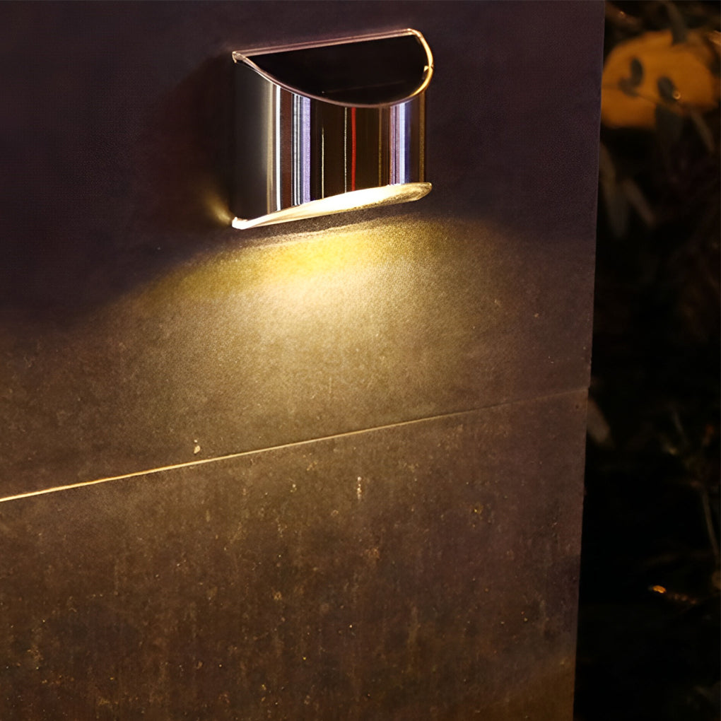 Stainless steel wall lamp with a curved top, casting a focused beam on a dark wall.