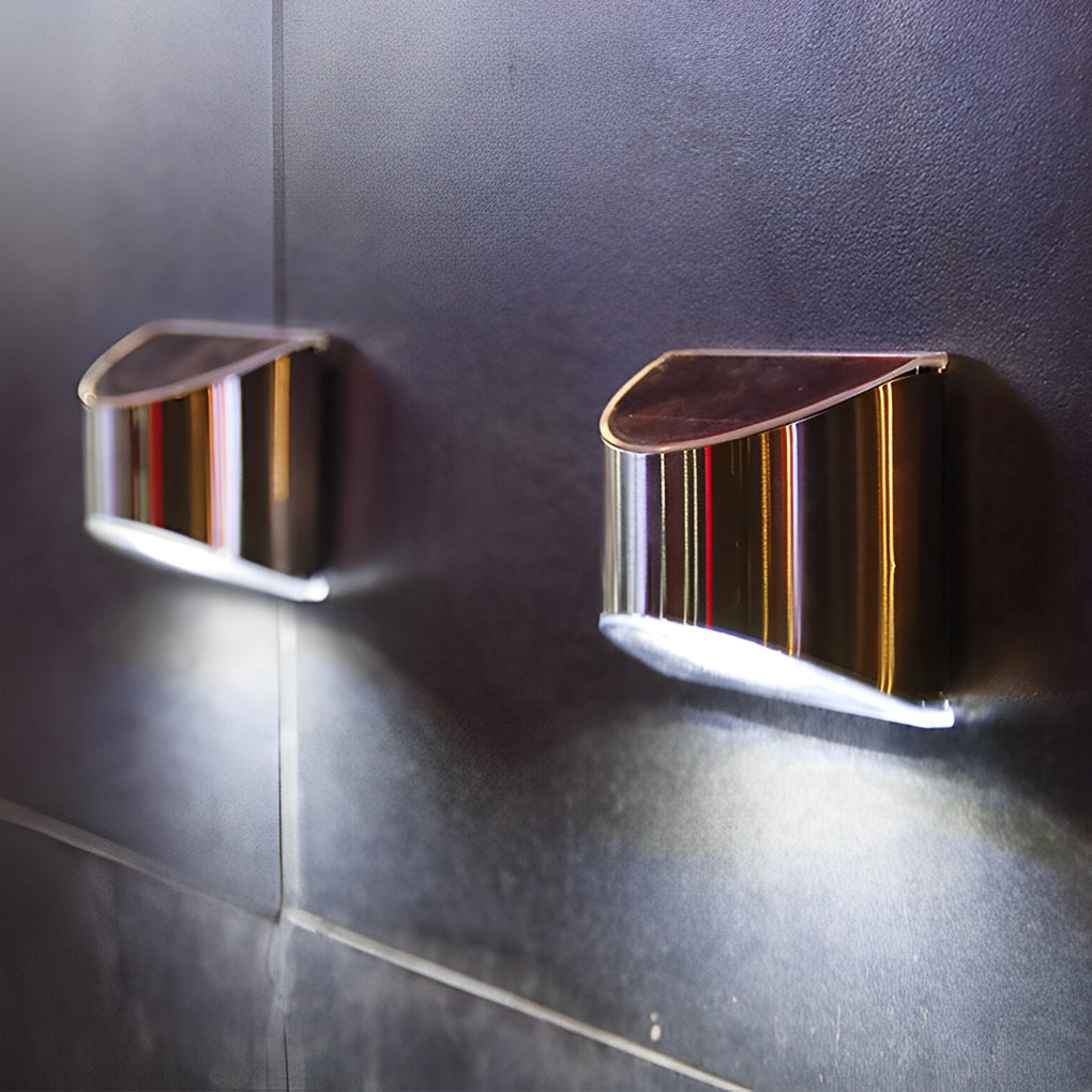 Stainless steel wall lamp with a sleek finish, glowing warmly in a rain setting.