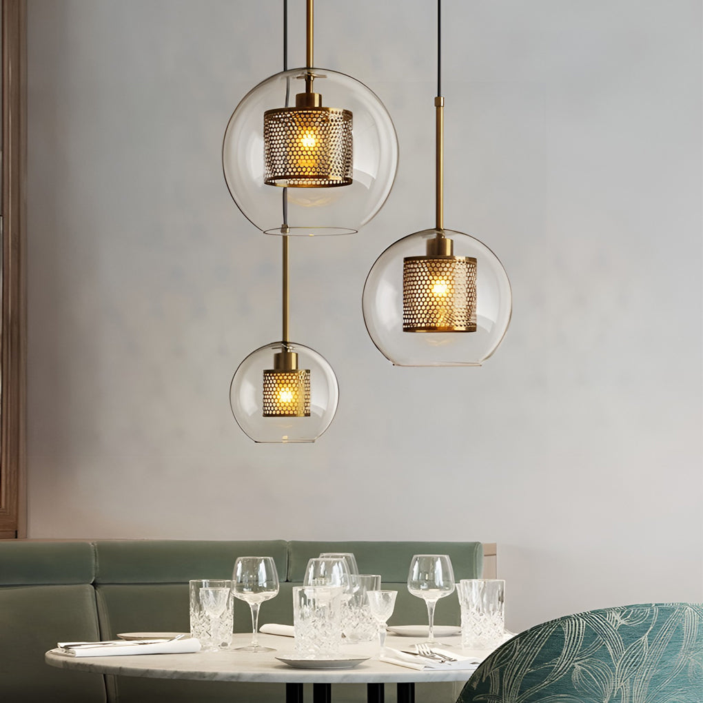 Trio of spherical Clear Glass Globe Pendant lights with brass mesh in a chic restaurant.