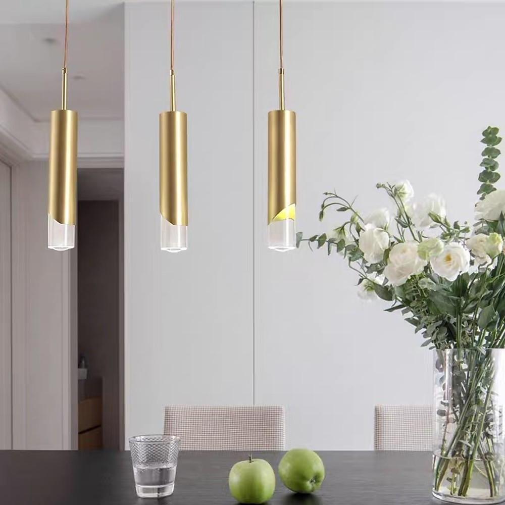 Trio of Slanted Gold Cylinder Pendant lights at staggered heights over a modern dining room.