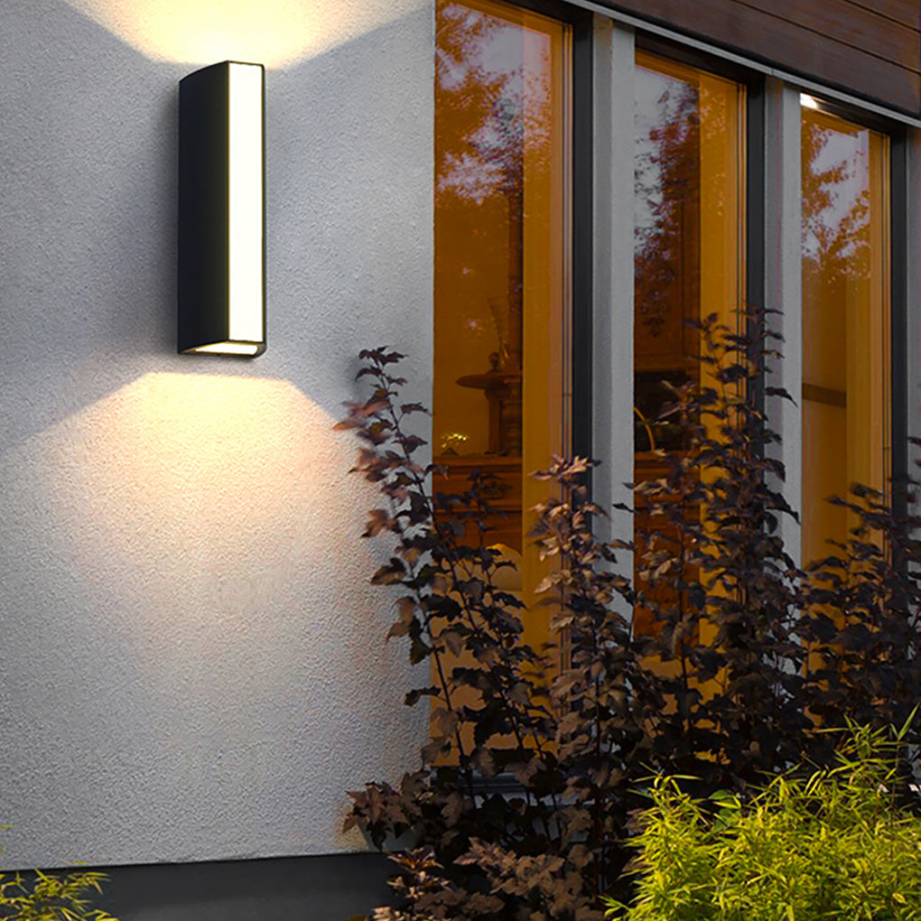 Modern up down cylinder sconce beside large windows, emphasizing vertical lines and enhancing exterior nighttime aesthetics.
