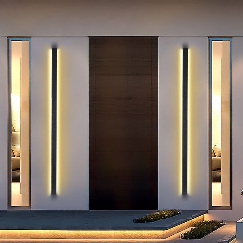 Long black outdoor lights with vertical LED glow, enhancing the modern entrance of a seaside residence.