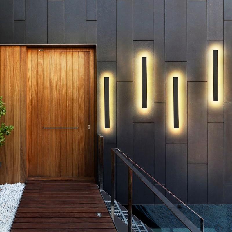 Long outdoor wall lights with vertical LED strips, mounted beside bookshelf for contemporary indoor-outdoor lighting.