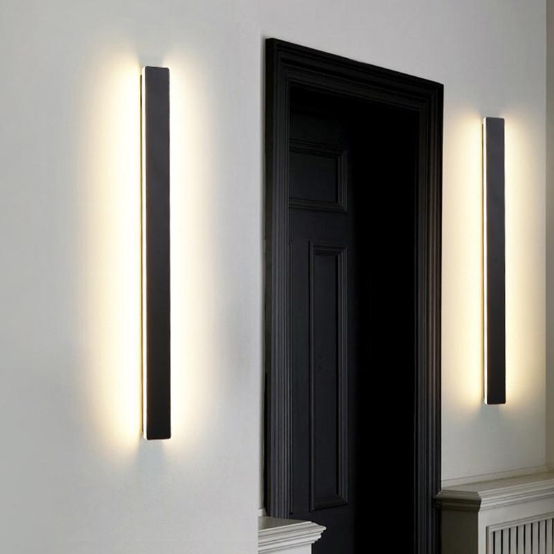 Long outdoor wall lights with vertical LED glow, installed on textured wall for contemporary outdoor ambiance.