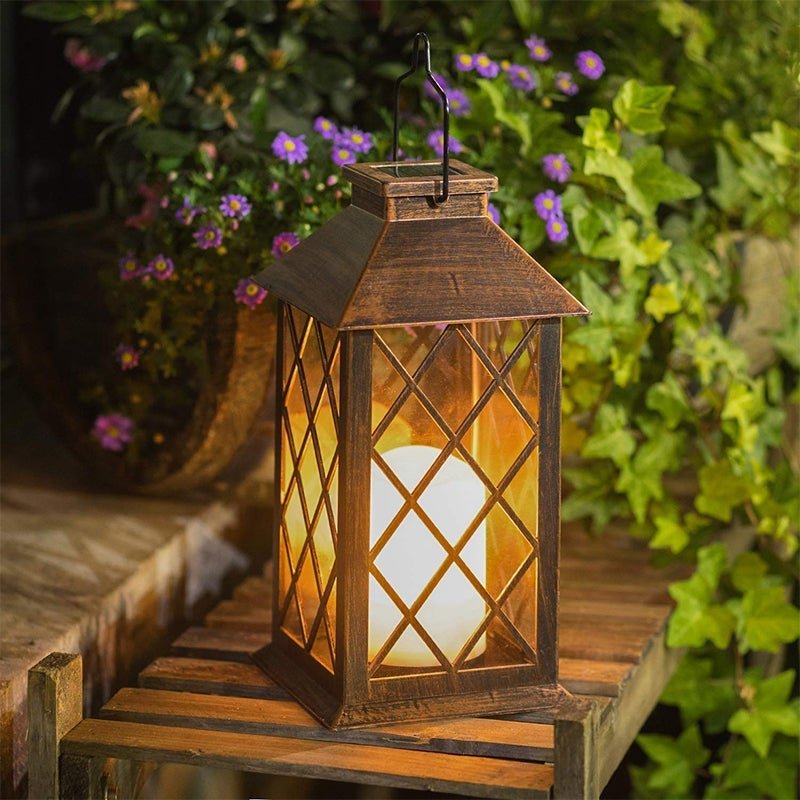 Vintage garden lanterns hanging on a garden hook with a warm glow.