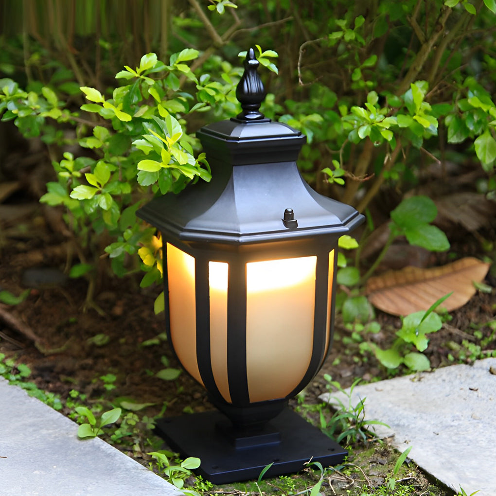 A vintage outdoor pillar lantern with warm glowing frosted glass set in a lush green garden way.