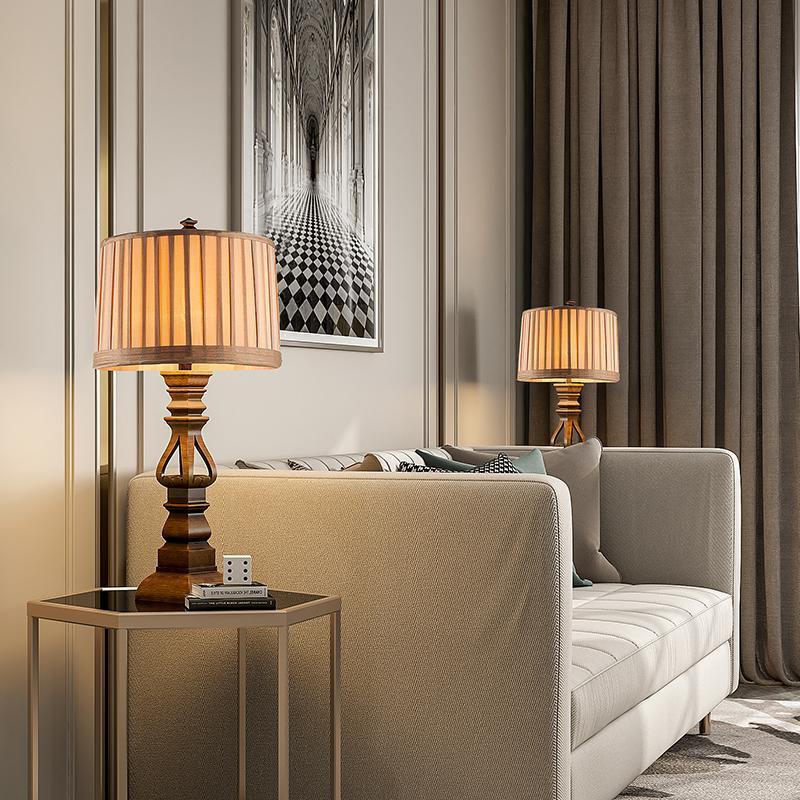 Vintage wood table lamp with a beige shade, illuminating a cozy living room corner.