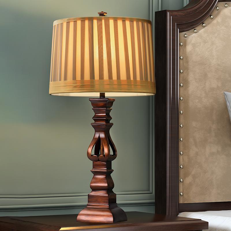 Vintage wood table lamp with a beige shade, providing warm light in a stylish room.