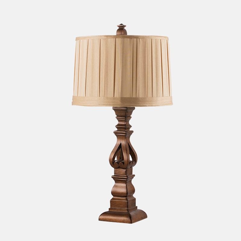 Vintage wood table lamp with a beige shade, placed on a wooden cabinet.