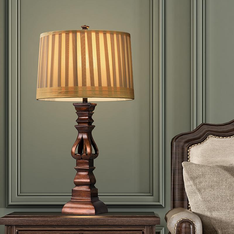 Vintage wood table lamp with a striped shade, placed on a wooden desk.