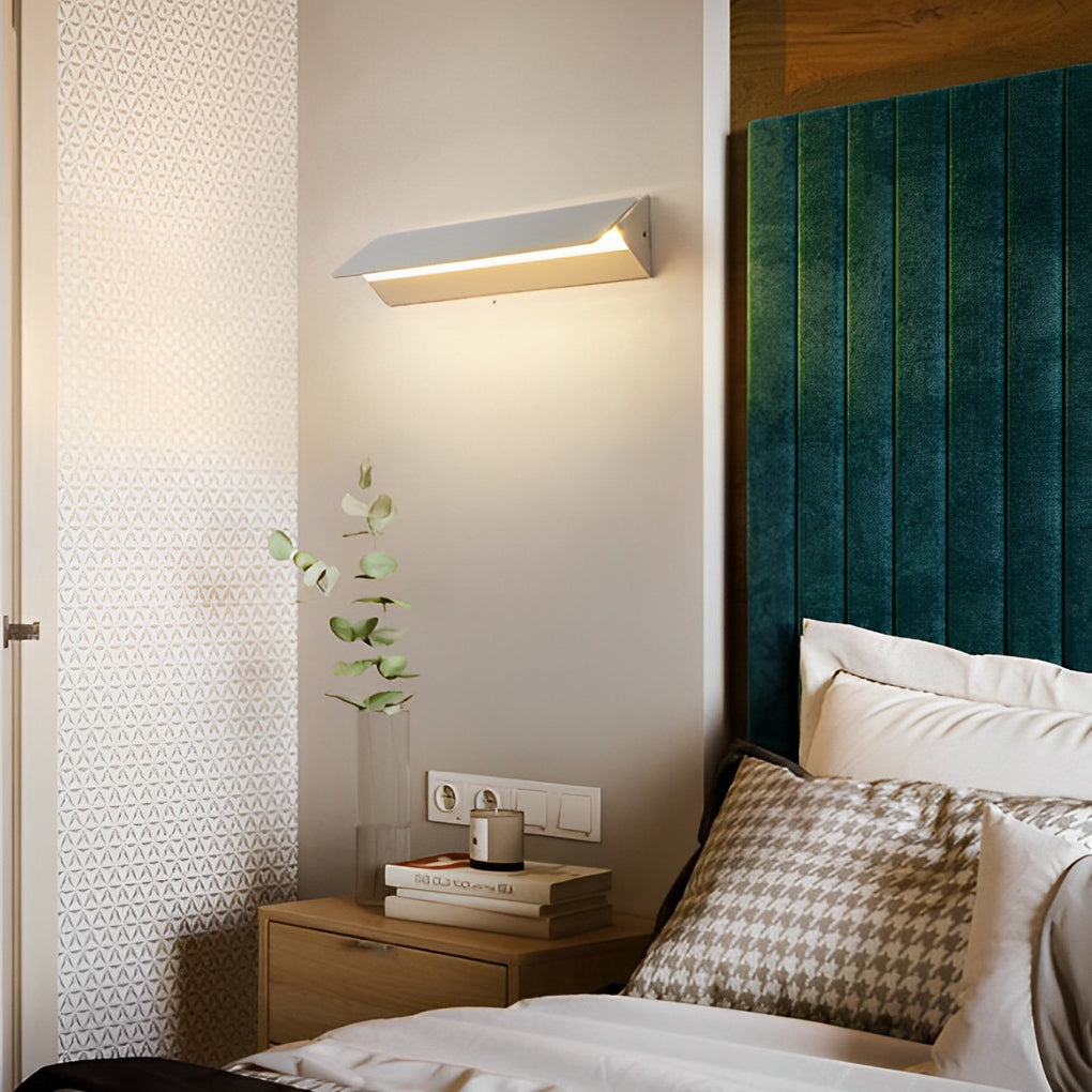Wall adjustable light installed beside bed with warm light glow.