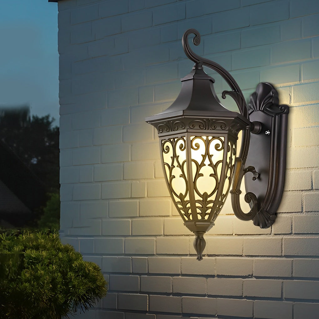 Wall sconce lantern with a classic bronze finish, glowing softly in a garden setting.