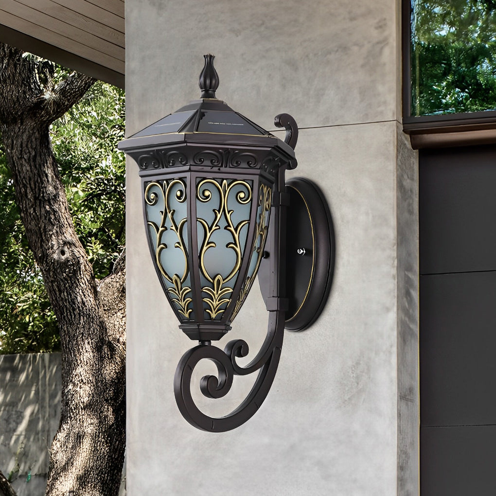 Wall sconce lantern with a decorative bronze finish, providing warm light in a garden.