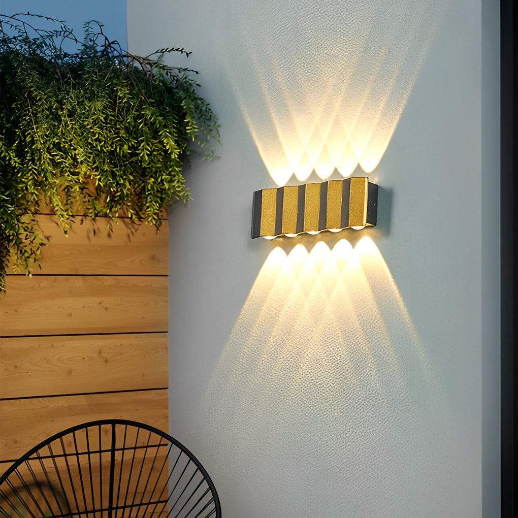Wall sconce up-down light providing warm light beside a decorative plant.