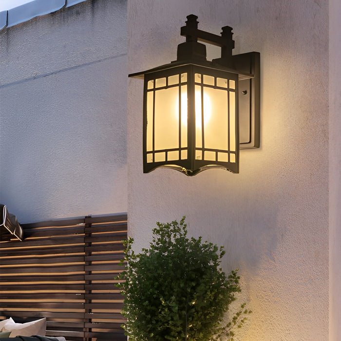 Lantern wall sconce with warm light glowing through frosted glass panels on modern wall.