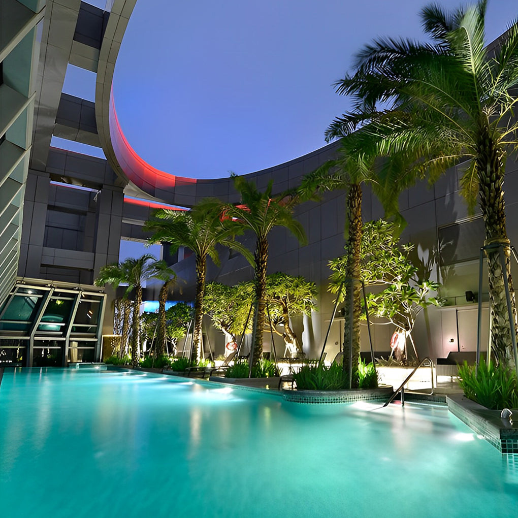 Waterproof outdoor spotlights casting a warm glow on a pool area surrounded by tropical plants.