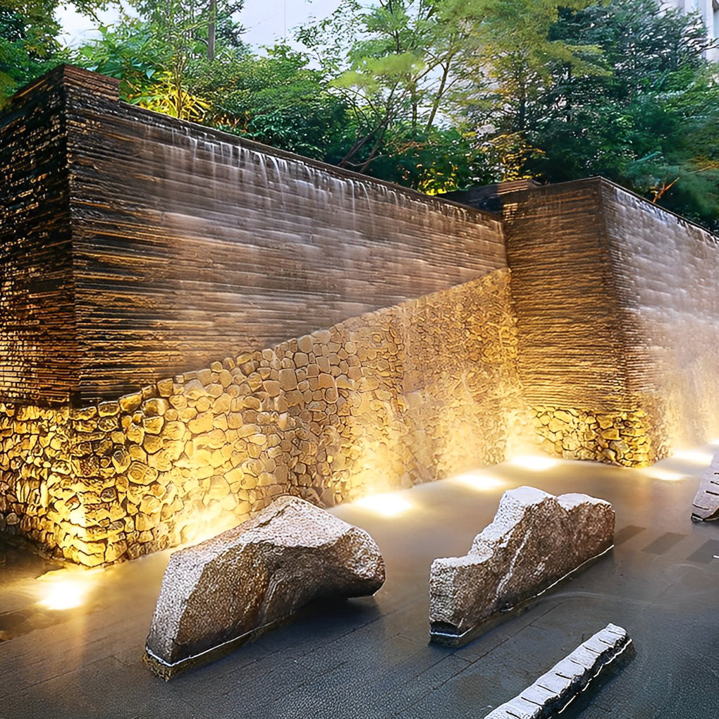 Waterproof outdoor spotlights illuminating a stone waterfall wall, creating a dramatic nighttime effect.