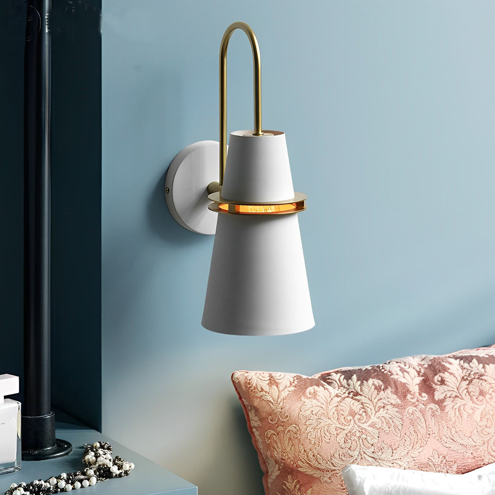 White cone wall lamp with brass detail mounted on blue bedroom accent wall.
