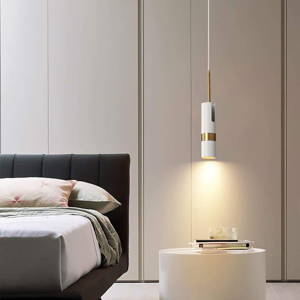 Elegant white adjustable cylindrical pendant light illuminates a minimalist bedroom's bedside.