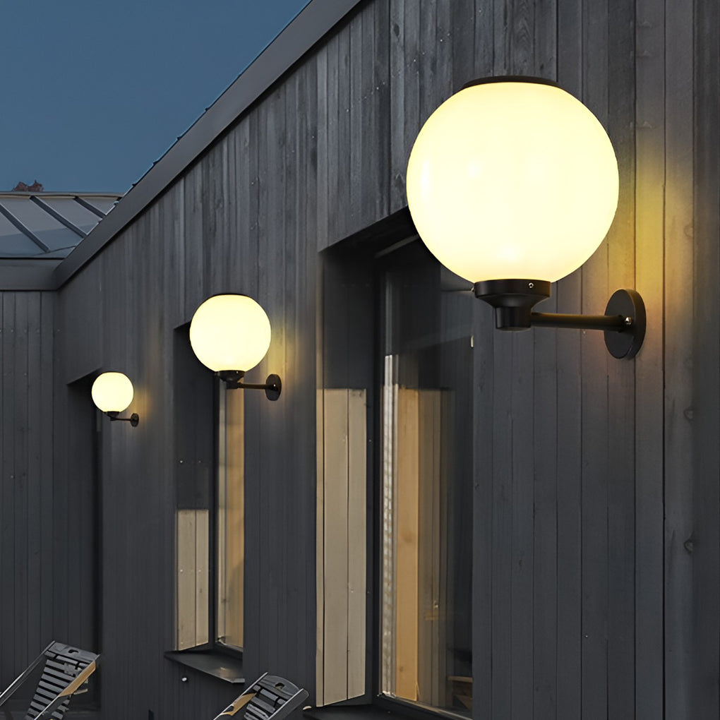 White outdoor globe wall sconce providing elegant illumination for a contemporary house exterior.
