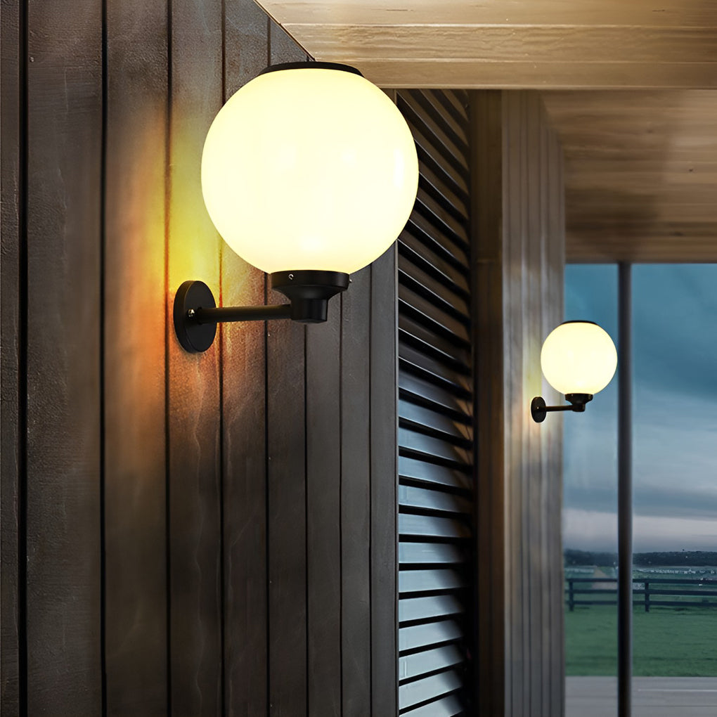 White outdoor globe wall sconce illuminating a cozy outdoor corner with directional glow.