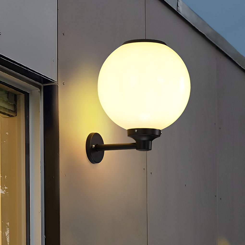 White outdoor globe wall sconce illuminating a minimalist outdoor wall with focused glow.