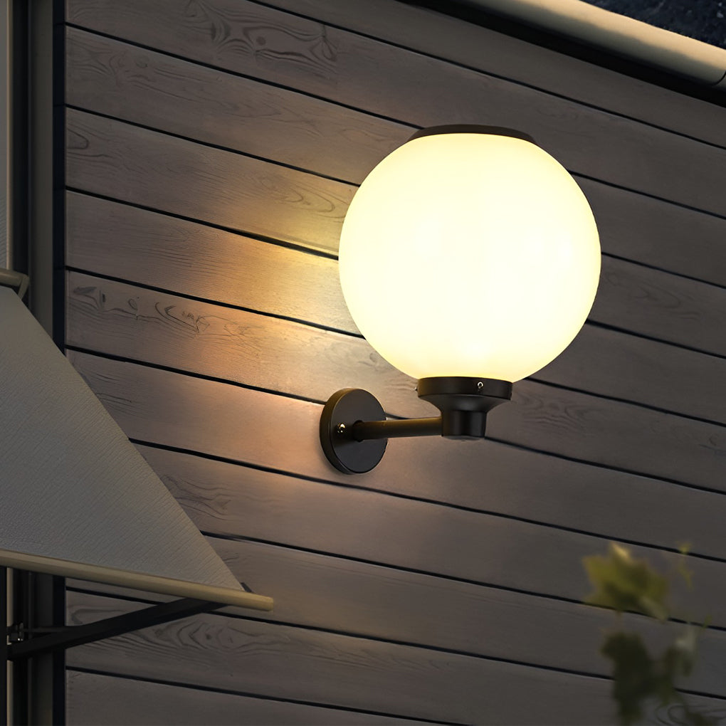 White outdoor globe wall sconce providing soft illumination along a stylish garden pathway.