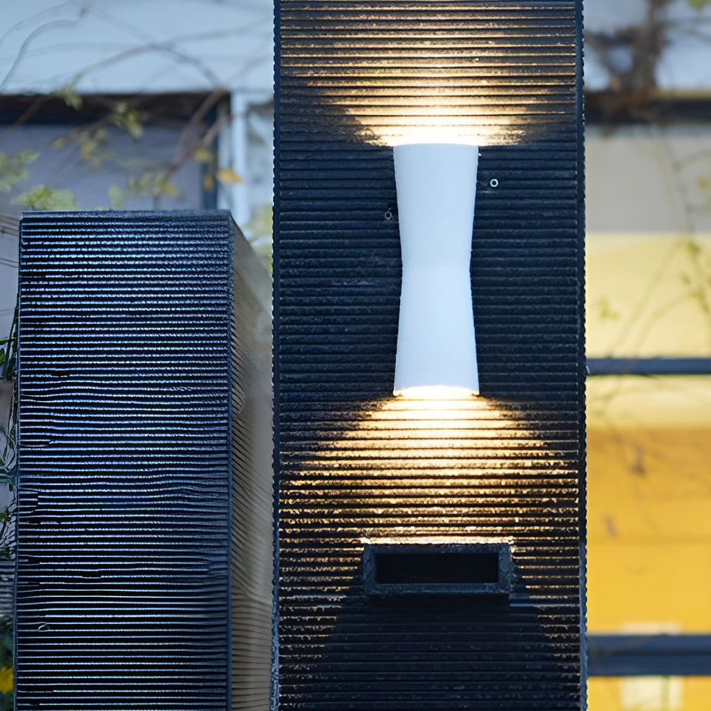 White up and down exterior wall light casting symmetrical light beams on textured wall surface.