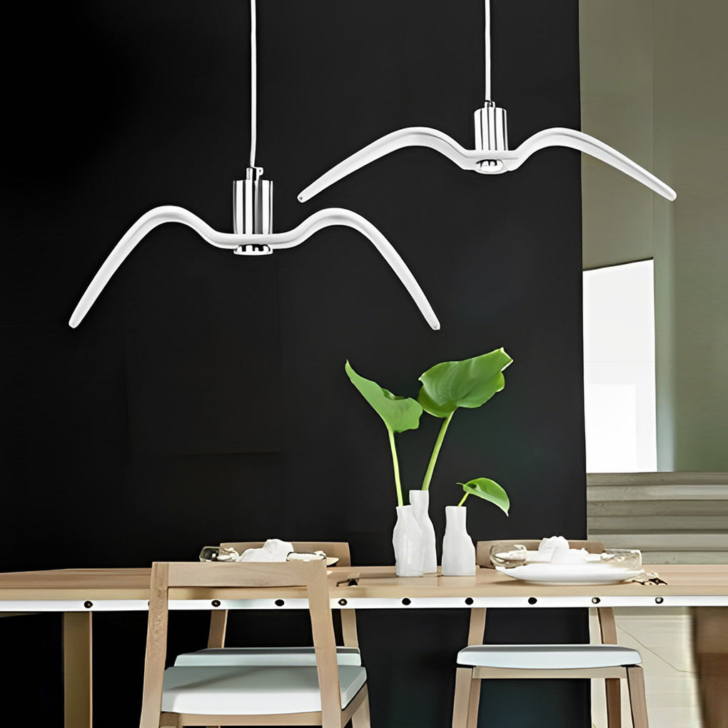 White wing pendant light displayed against a dark wall over a dining table.