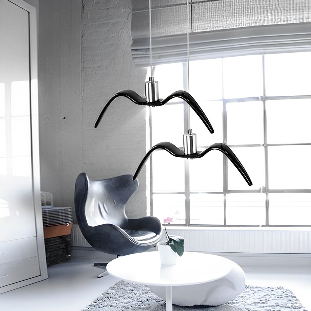 Black wing pendant light in a bright loft-style interior with large windows.