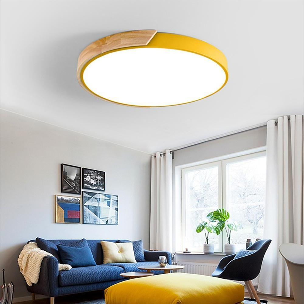 Yellow nordic wooden ceiling light illuminating a bright living room with a cozy blue sofa ok.
